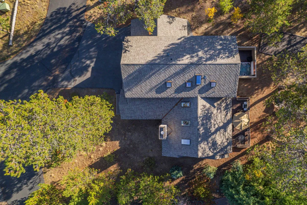 The image captures the roof structure and outdoor seating area nestled among lush greenery, offering a tranquil spot to relax and connect with nature. The deck area beckons for sunset views and stargazing.