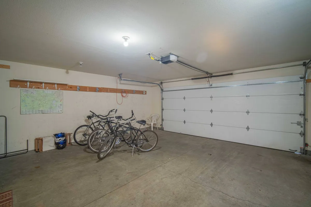 Inside the garage, several bicycles are neatly stored alongside a map on the wall and an empty chair, creating a sense of readiness for outdoor exploration. The setup is organized and practical, emphasizing biking adventures and easy access to the trails.